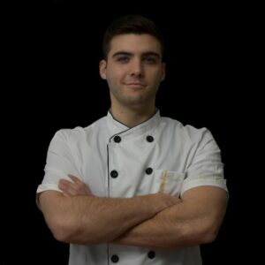 Elijah Cady in a chef outfit in front of a black backdrop