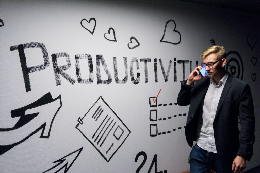 Man on phone in front of board that says productivity