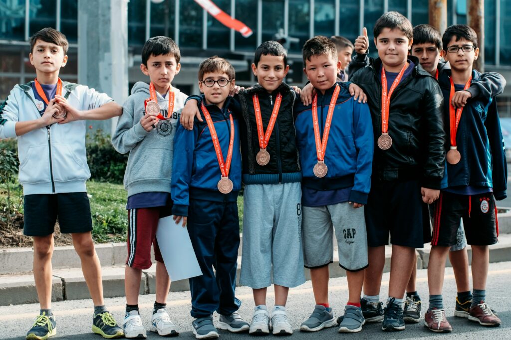 group of children wearing medal standing near wall
