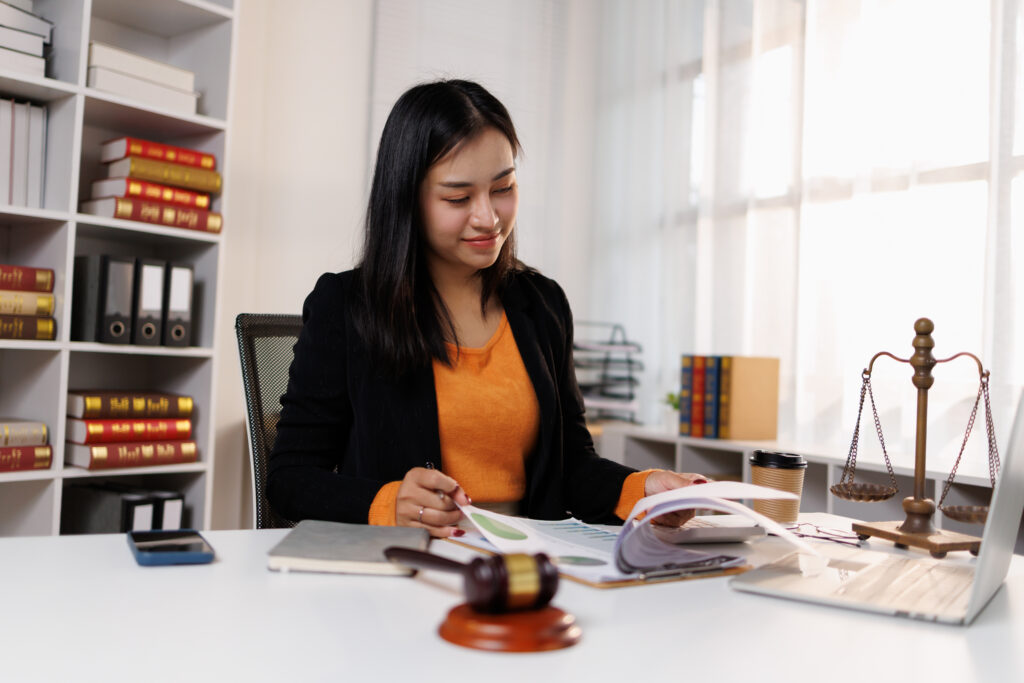 Female lawyer working at office desk reviewing legal documents, providing professional counsel while managing legal affairs and client cases with expertise